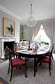 Set dining table with glass chandelier in contemporary London home England, UK