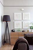 Braune Stehlampe und Kunstwerk über hölzernem Sideboard in modernem Wohnzimmer, Hove, East Sussex, England, UK