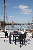 Tisch und Stühle auf einem Londoner Hausboot mit Blick auf die Themse