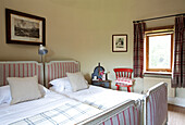 Checked and striped fabrics in twin bedroom of Kent farmhouse England UK