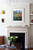 Modern art above fireplace with cut flowers in contemporary Herefordshire family home England UK
