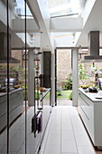 White galley kitchen with open back door in contemporary London townhouse, England, UK