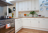 Cream fitted kitchen with stainless steel range oven in London townhouse, UK