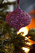 Lila Weihnachtskugel mit Juwelen hängt am Weihnachtsbaum in einem Londoner Haus, UK