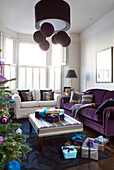 Christmas presents on floor near striped ottoman in living room of contemporary London home, UK