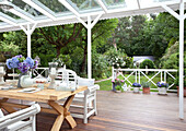 Bemalte Sitzbank am Holztisch auf der überdachten Holzterrasse eines Hauses in London, UK