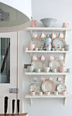 Pink and blue pastel chinaware in shelves in kitchen of contemporary London home, UK