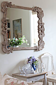 Verschnörkelter Spiegel mit Blumenarrangement im Wohnzimmer eines Landhauses an der Küste von Sussex, England, UK
