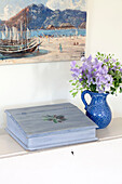 Schnittblumen und eine hellblaue Schreibbox mit Kunstwerken in einem Cottage an der Küste von Sussex, England, UK