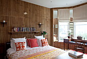 Double bed with wood effect wall and bay window in London townhouse, England, UK