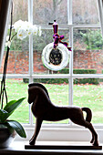 Glaskugel am Fenster eines Bauernhauses in Surrey mit Orchidee und Pferdestatue, England, Vereinigtes Königreich