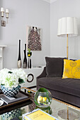 Gelbes Kissen und Stehlampe mit Vasen auf Couchtisch im Wohnzimmer einer Londoner Wohnung, UK