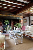 Cut flowers on coffee table in beamed living room in Maidstone farmhouse, Kent, England, UK