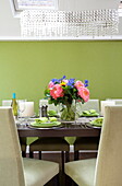 Floral centrepiece on dining table in lime green room of contemporary London townhouse, England, UK