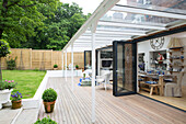 Long dining table in open plan living area with bi-fold doors view from the garden Dulwich home, London, UK