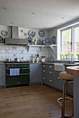 Pastel blue fitted kitchen with green range oven in historic Sussex country home England UK