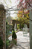 Blick durch die Pforte auf die gepflasterte Terrasse des historischen Landhauses in Sussex England UK