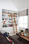 Bücherregal mit Zugangsleiter im Wohnzimmer eines modernen Landhauses in Surrey, England