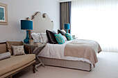 Turquoise lamps in cream bedroom of contemporary Surrey country home England UK