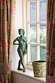 Figurine of naked woman with flowerpot on windowsill in Sussex home England UK
