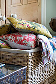 Assorted cushions and blanket in wicker basket Sussex home England UK