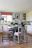 Pink seat cushions on chairs at kitchen table in Sussex home, England, UK