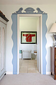 View through light blue doorframe to framed Chinese jacket in bathroom of Sussex home, England, UK