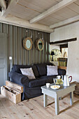 Coffeepot on table with black sofa in living room of Brittany cottage Western France