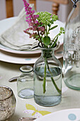 Schnittblumen in alten Flaschen auf dem Küchentisch in einem Haus in Sussex Downs, England UK
