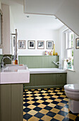 Panelled green bathroom with chequered floor in bathroom of Sussex Downs home, England, UK
