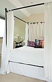 Four poster bed with Bollywood print cushions in contemporary home, Kingston upon Thames, England, UK