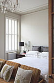 Sofa with cushions at foot of bed in London townhouse, England, UK