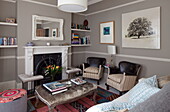 Pair of vintage armchairs and velvet ottoman footstool in living room of London home, England, UK