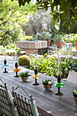 Hurricane lamps and cut roses on wooden table on terrace of French holiday villa