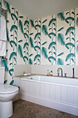 Türkisfarbene Blattmustertapete im weißen Badezimmer eines Hauses in Herefordshire, England, UK