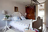 Toile du jouy cushions on double bed with wooden wardrobe in West Sussex bedroom, England, UK