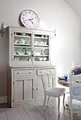 Chinaware in kitchen dresser with clock in West Sussex home England UK