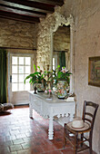 Large mirror on painted side table in exposed stone hallway of French farmhouse in the Loire, France, Europe