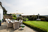 Gartenmöbel aus Weidengeflecht mit Sonnenschirm auf der Terrasse eines Hauses in West Maling, Kent, England, UK