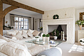 Gingham cushions on cream sofa with glass-topped coffee table in beamed West Mailing living room, Kent, England, UK