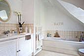 Circular mirror and orchid on wash stand in bathroom with cream tiled splashbacks in West Mailing home Kent England UK