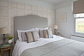 Striped cushions with trompe l'oeil wallpaper in bedroom of London townhouse, England, UK