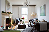 Lit candles with dark brown leather sofa in London home, England, UK