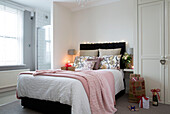 Helles Licht auf einem Doppelbett mit rosa Decken in einem Haus in London, England, UK