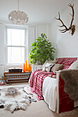 Antlers above sofa with animal fur in living room of London home, England, UK