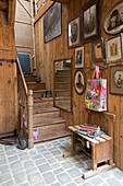 Schwarz-Weiß-Fotografien und Oldtimer-Roller im Holztreppenhaus eines französischen Bauernhauses