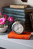Antique alarm clock on hardbacked book with cut flowers in French farmhouse