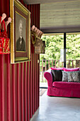 Gerahmter Druck und Kleiderhaken mit rosafarbenem Sofa in einem bretonischen Landhaus, Frankreich