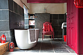 Freistehende Badewanne mit rotem Anstrich in einem mit Schiefer gefliesten Badezimmer, Landhaus in der Bretagne, Frankreich