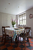 Dining table with wooden chairs on terracotta and black tiled floor in Ceredigion farmhouse Wales UK